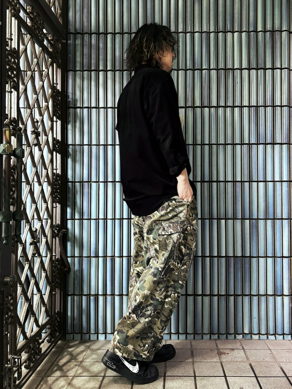 グリーン系のカーゴパンツ、ブラック系のスニーカー、ブラック系のシャツ/ブラウスを着用したメンズの春コーディネートの4枚目の写真