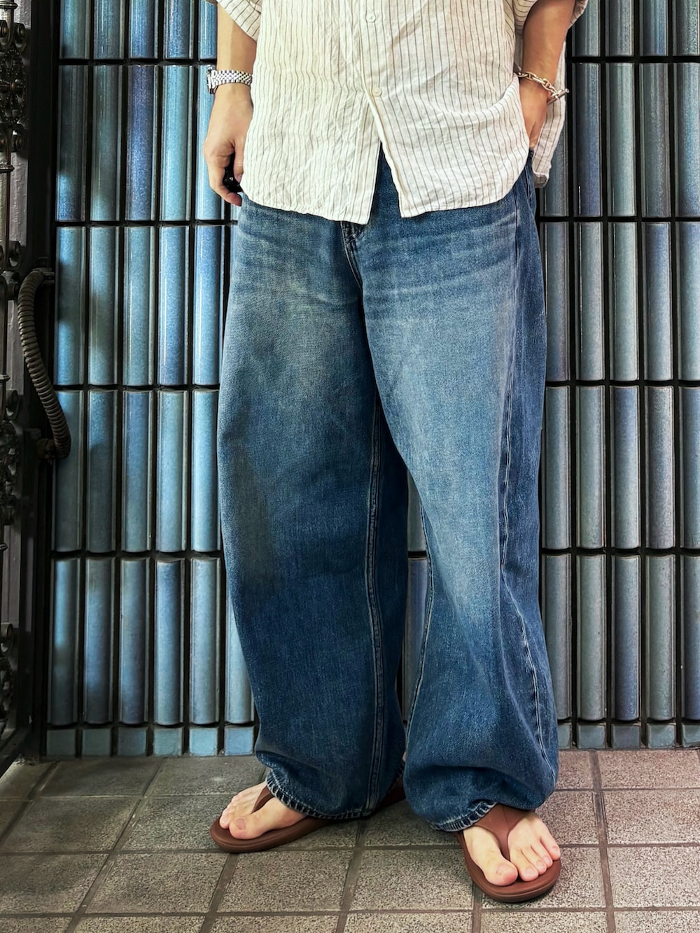 ブラウン系のサンダル、ホワイト系のシャツ/ブラウス、ブルー系のデニムパンツを着用したメンズの夏コーディネートの3枚目の写真