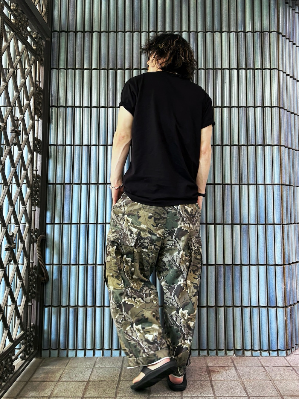 グリーン系のカーゴパンツ、ブラック系のサンダル、ブラック系のTシャツ/カットソーを着用したメンズの夏コーディネートの4枚目の写真