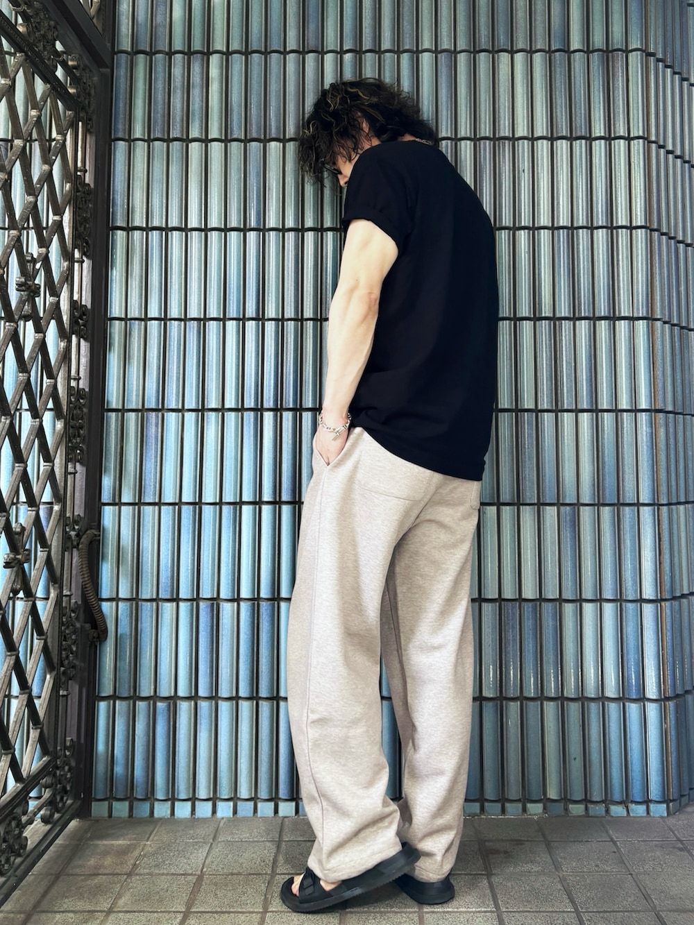 ブラック系のサンダル、ブラック系のTシャツ/カットソー、ベージュ系のスウェットパンツを着用したメンズの夏コーディネートの4枚目の写真