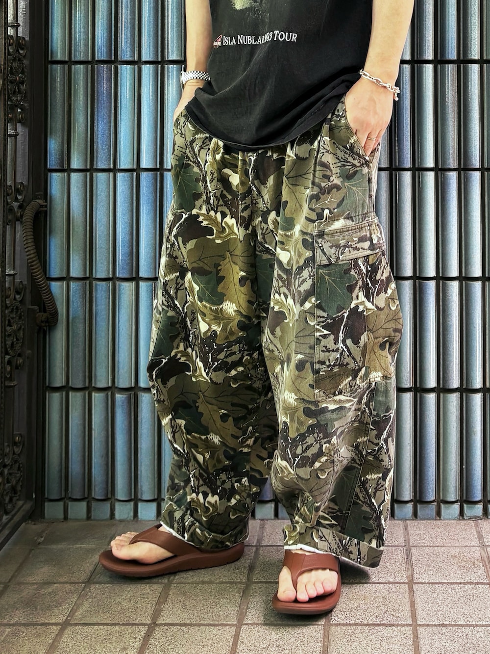 ブラウン系のサンダル、グリーン系のカーゴパンツ、ブラック系のTシャツ/カットソーを着用したメンズの夏コーディネートの3枚目の写真