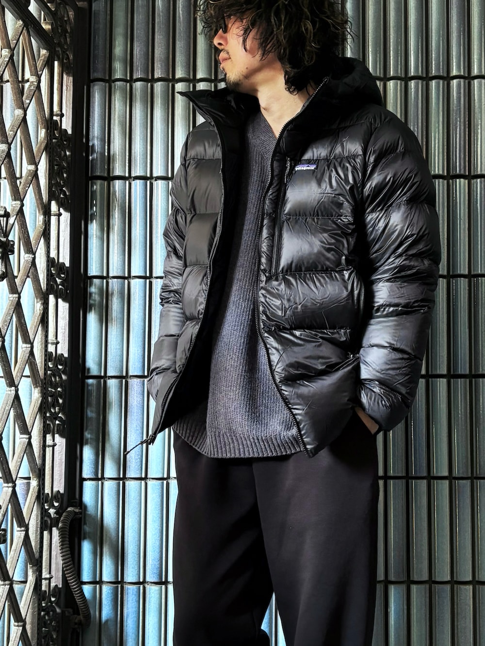 グレー系のニット/セーター、ブラック系のダウンジャケット/コート、ブラック系のスウェットパンツを着用したメンズの冬コーディネートの2枚目の写真