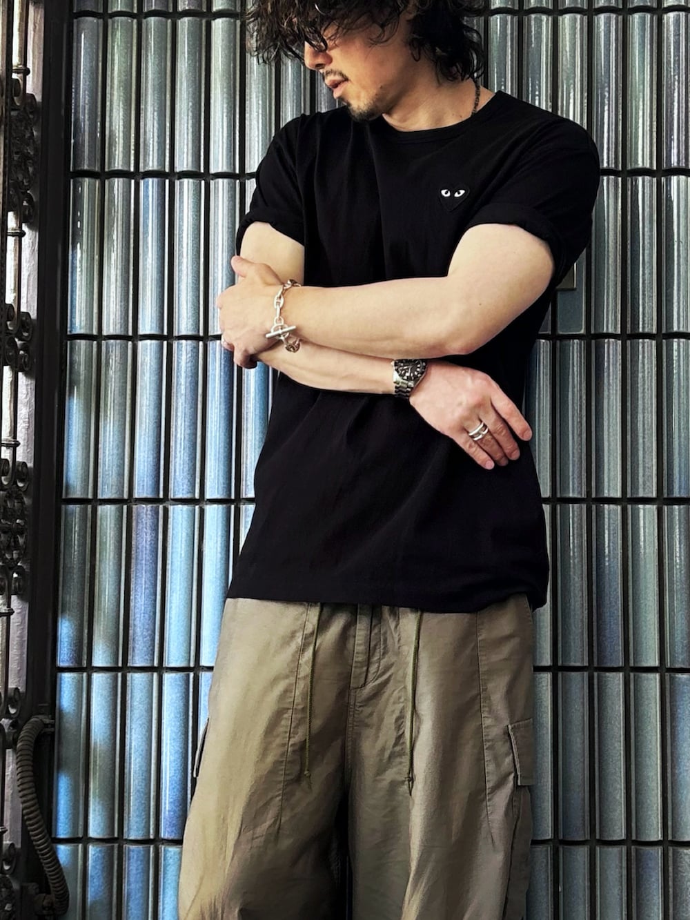 グリーン系のカーゴパンツ、ブラック系のサンダル、ブラック系のTシャツ/カットソーを着用したメンズの夏コーディネートの2枚目の写真