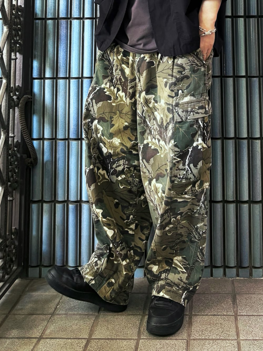 グリーン系のカーゴパンツ、ブラック系のスニーカー、グレー系のTシャツ/カットソーを着用したメンズの春コーディネートの3枚目の写真