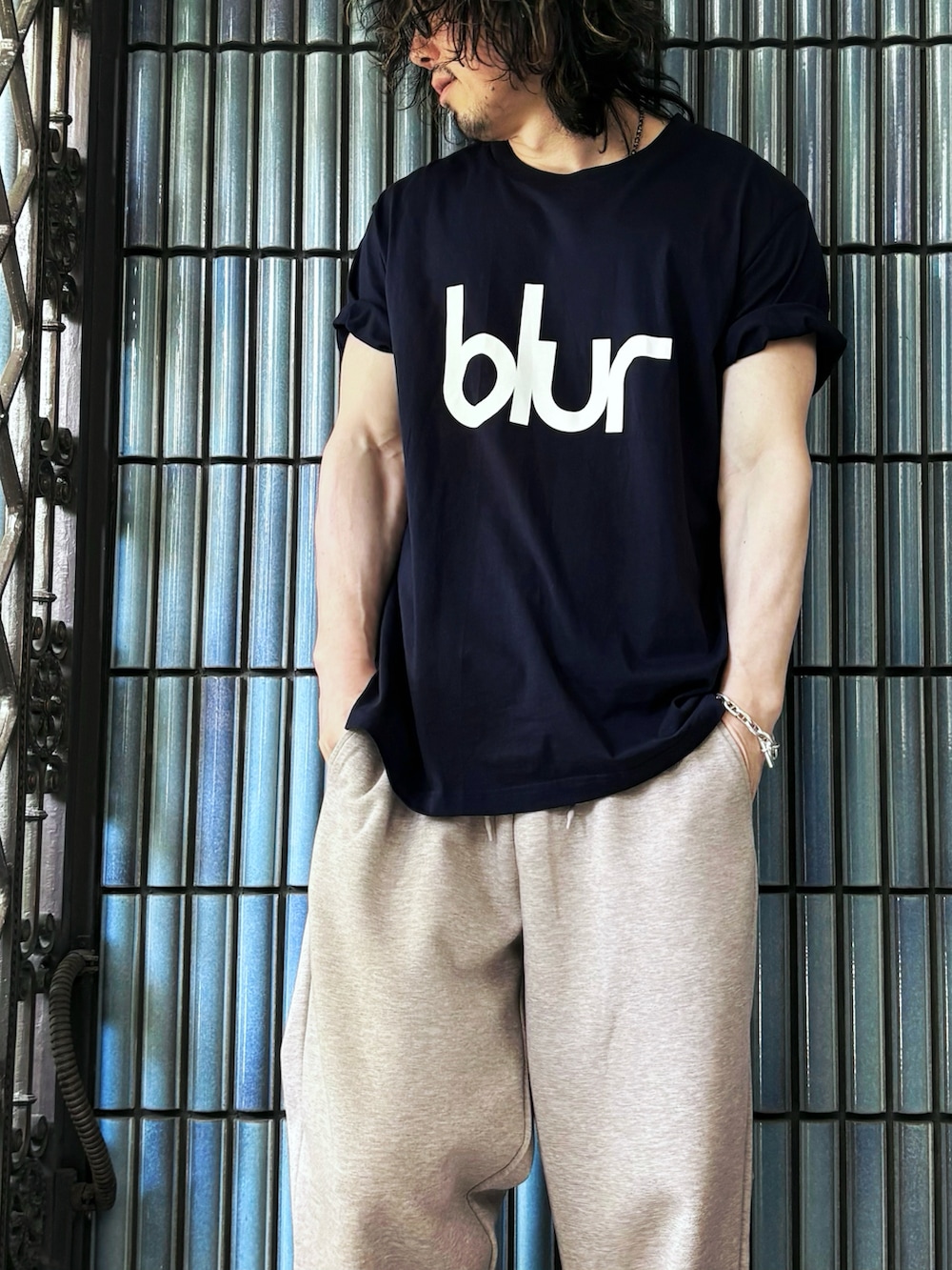 ブラック系のスニーカー、ブルー系のTシャツ/カットソー、ベージュ系のスウェットパンツを着用したメンズの春コーディネートの2枚目の写真