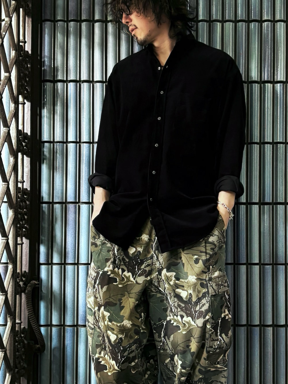 グリーン系のカーゴパンツ、ブラック系のスニーカー、ブラック系のシャツ/ブラウスを着用したメンズの春コーディネートの2枚目の写真