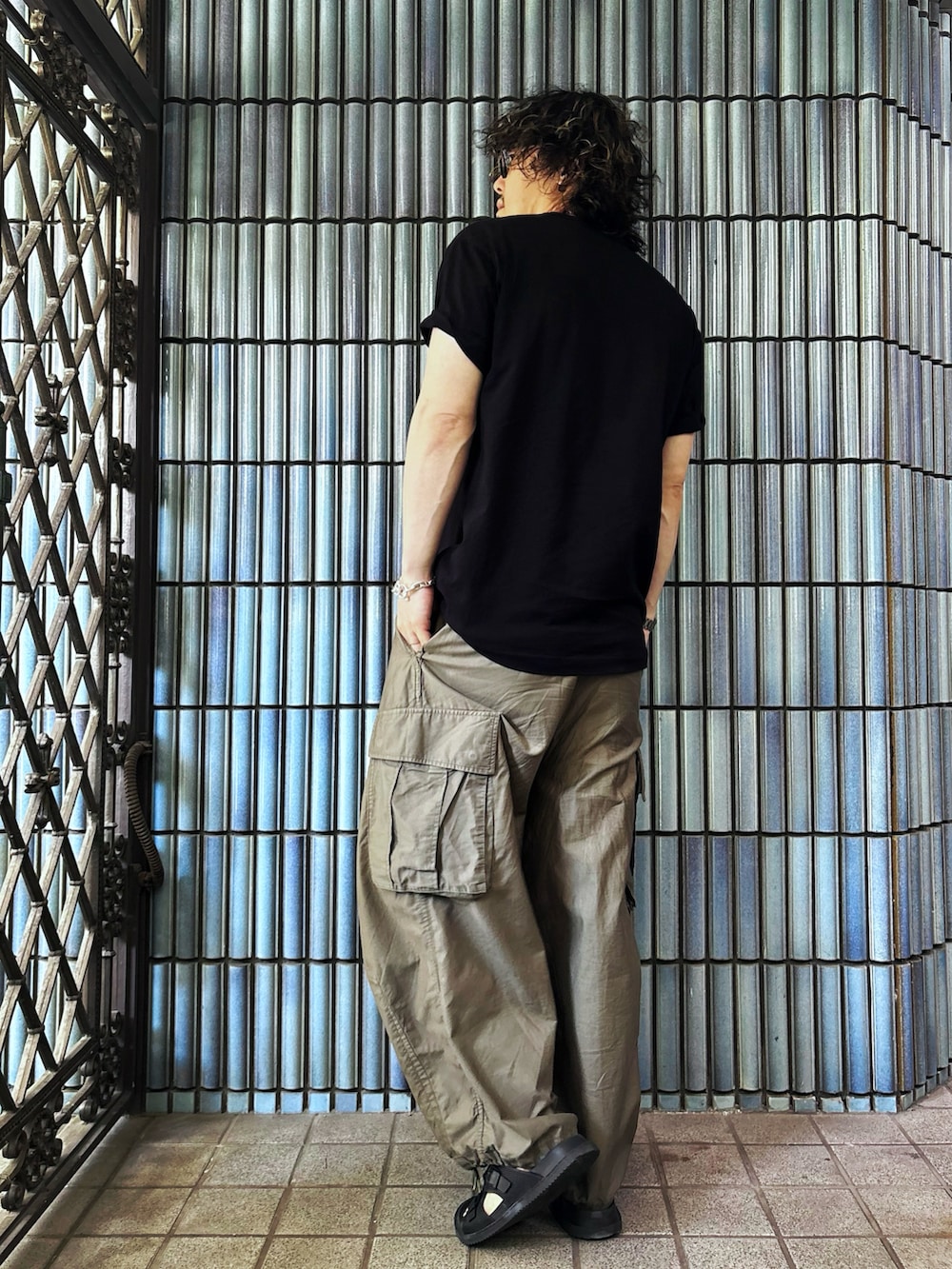 グリーン系のカーゴパンツ、ブラック系のサンダル、ブラック系のTシャツ/カットソーを着用したメンズの夏コーディネートの4枚目の写真