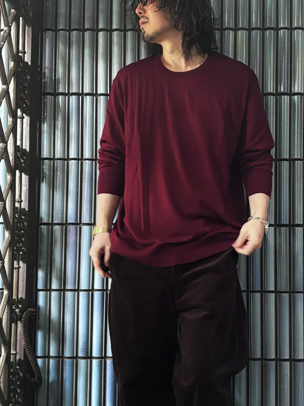 ブラック系のスニーカー、レッド系のニット/セーター、ブラウン系のその他パンツを着用したメンズの冬コーディネートの2枚目の写真