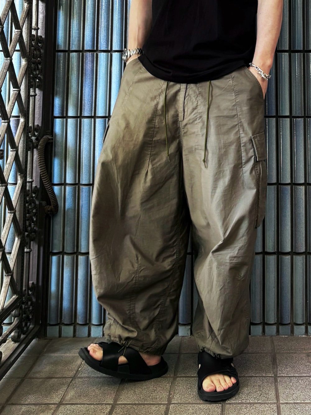 グリーン系のカーゴパンツ、ブラック系のサンダル、ブラック系のTシャツ/カットソーを着用したメンズの夏コーディネートの3枚目の写真