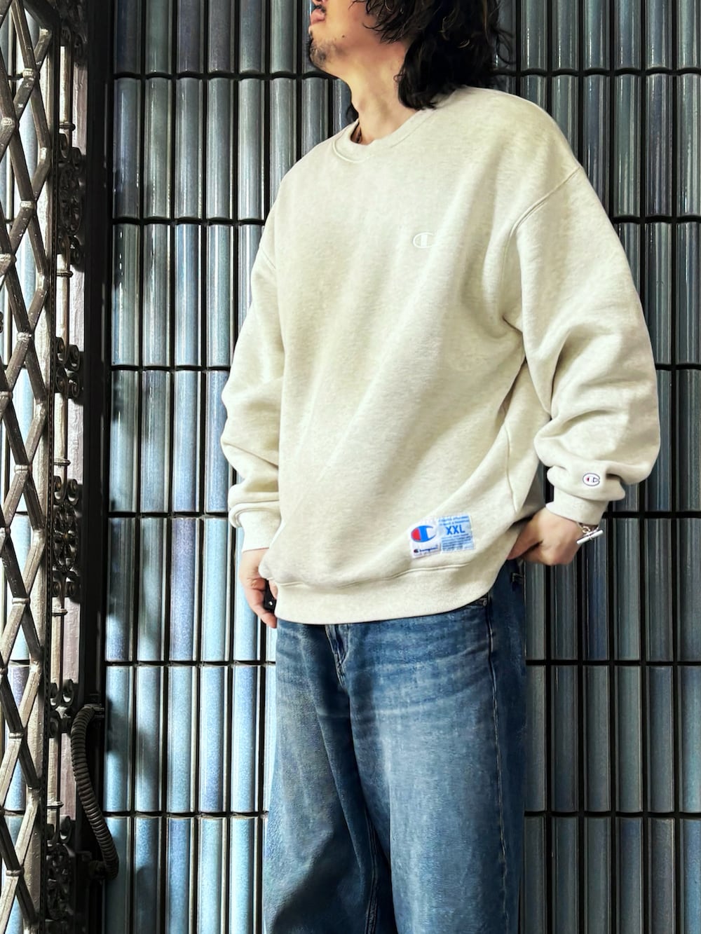 ベージュ系のスウェット、グレー系のスニーカー、ブルー系のデニムパンツを着用したメンズの春コーディネートの2枚目の写真