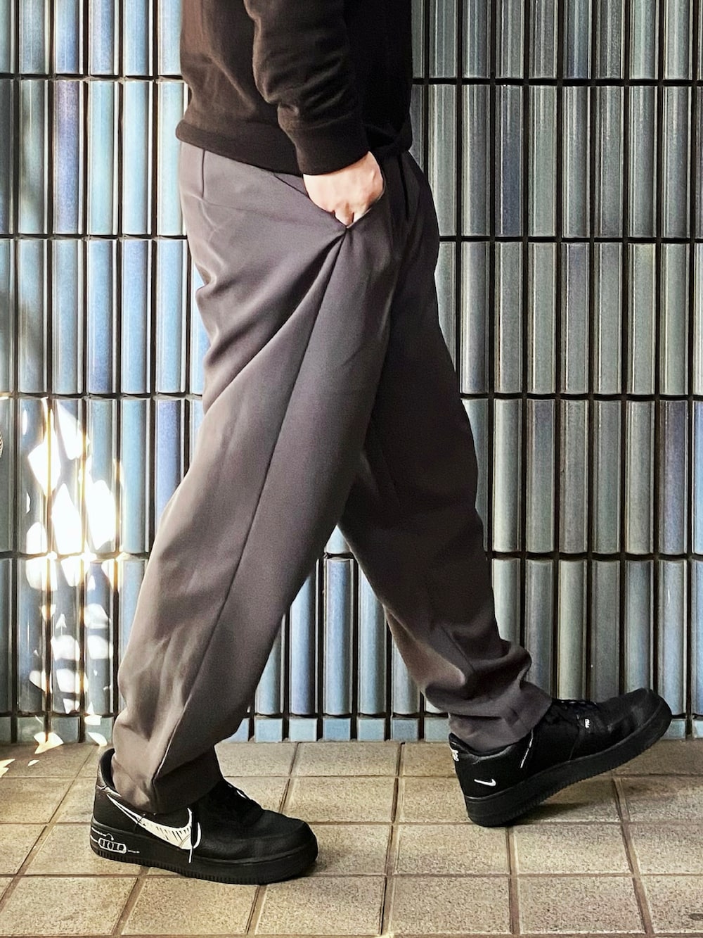 ブラウン系のポロシャツ、グレー系のその他パンツ、ブラック系のスニーカーを着用したメンズの春コーディネートの3枚目の写真