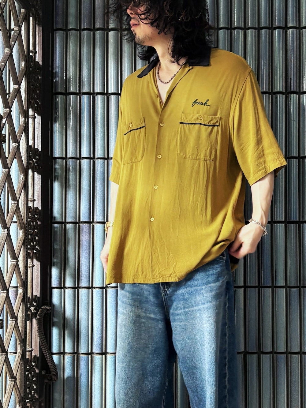 ブラック系のサンダル、イエロー系のシャツ/ブラウス、ブルー系のデニムパンツを着用したメンズの秋コーディネートの2枚目の写真