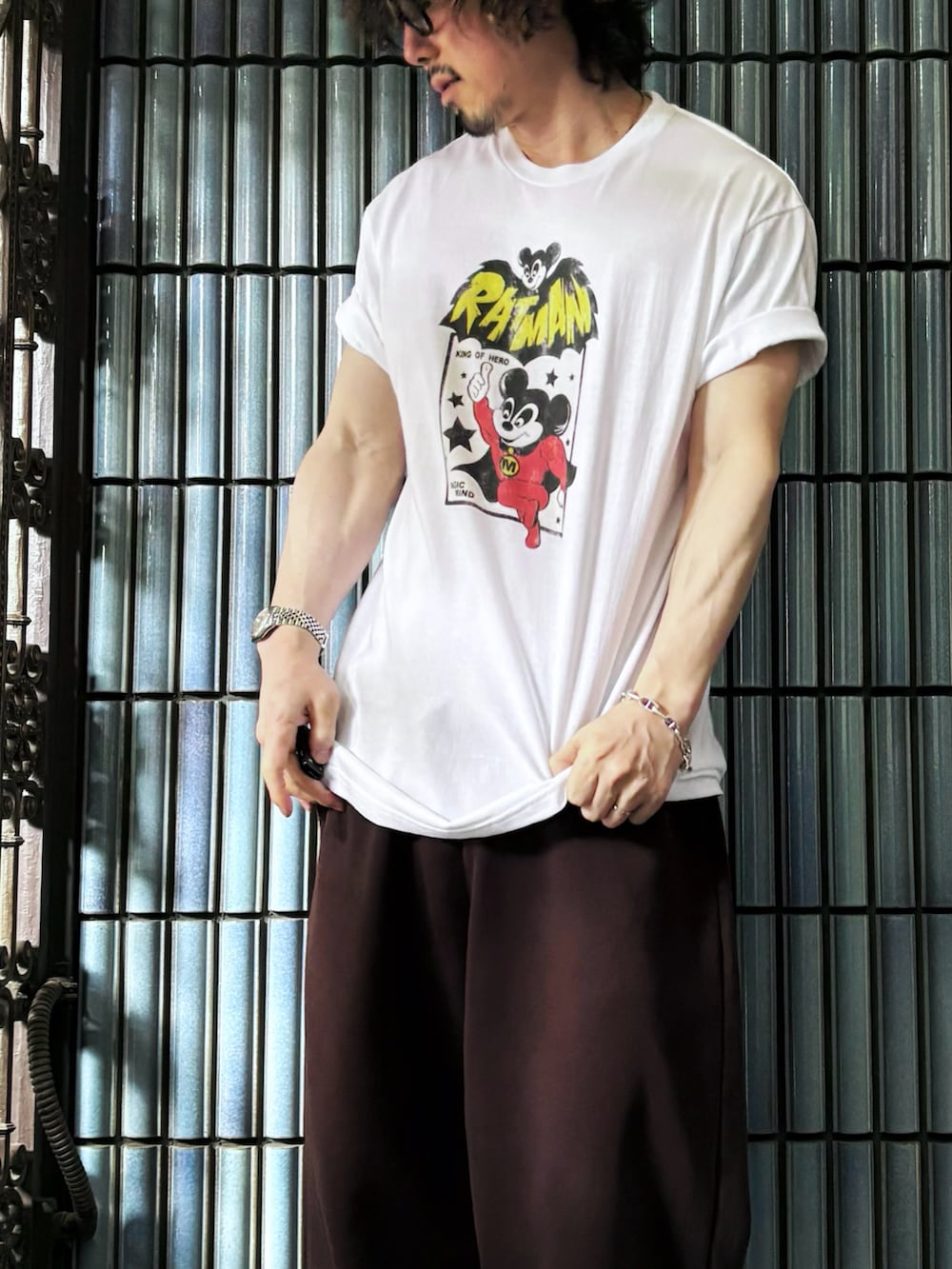 ブラック系のサンダル、ホワイト系のTシャツ/カットソー、ブラウン系のスウェットパンツを着用したメンズの夏コーディネートの2枚目の写真