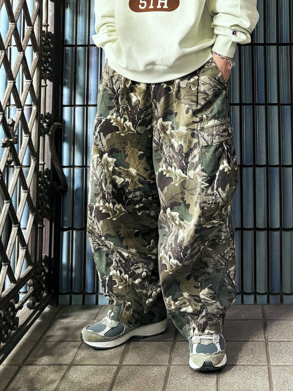 グリーン系のカーゴパンツ、ホワイト系のスウェット、グレー系のスニーカーを着用したメンズの春コーディネートの3枚目の写真