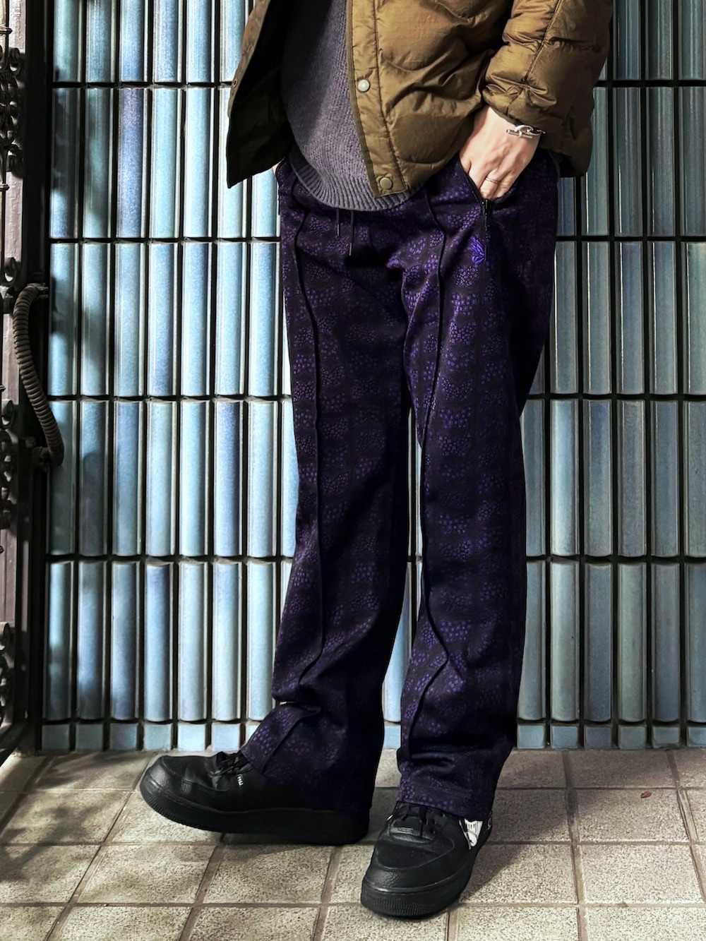 ブラック系のスニーカー、グレー系のニット/セーター、グリーン系のダウンジャケット/コートを着用したメンズの冬コーディネートの3枚目の写真