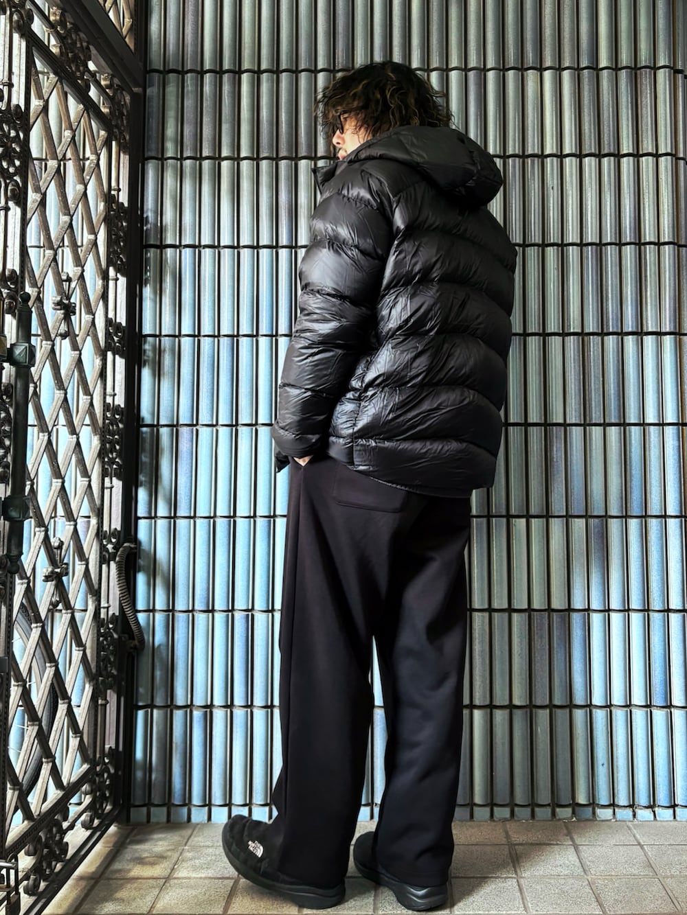 グレー系のニット/セーター、ブラック系のダウンジャケット/コート、ブラック系のスウェットパンツを着用したメンズの冬コーディネートの4枚目の写真