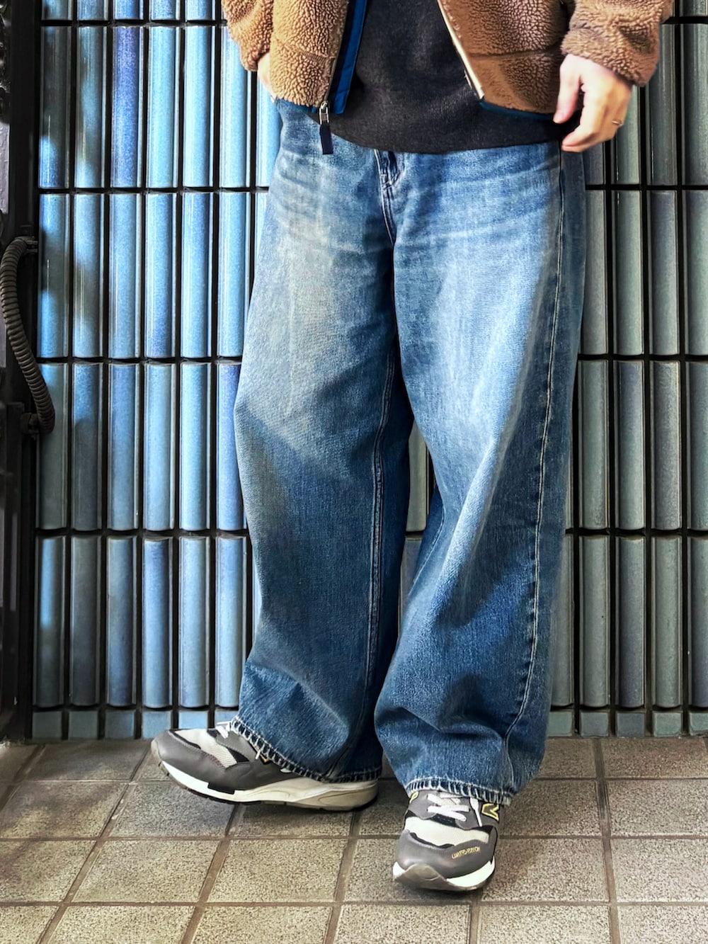 グレー系のスニーカー、グレー系のニット/セーター、ゴールド系のブルゾンを着用したメンズの冬コーディネートの3枚目の写真