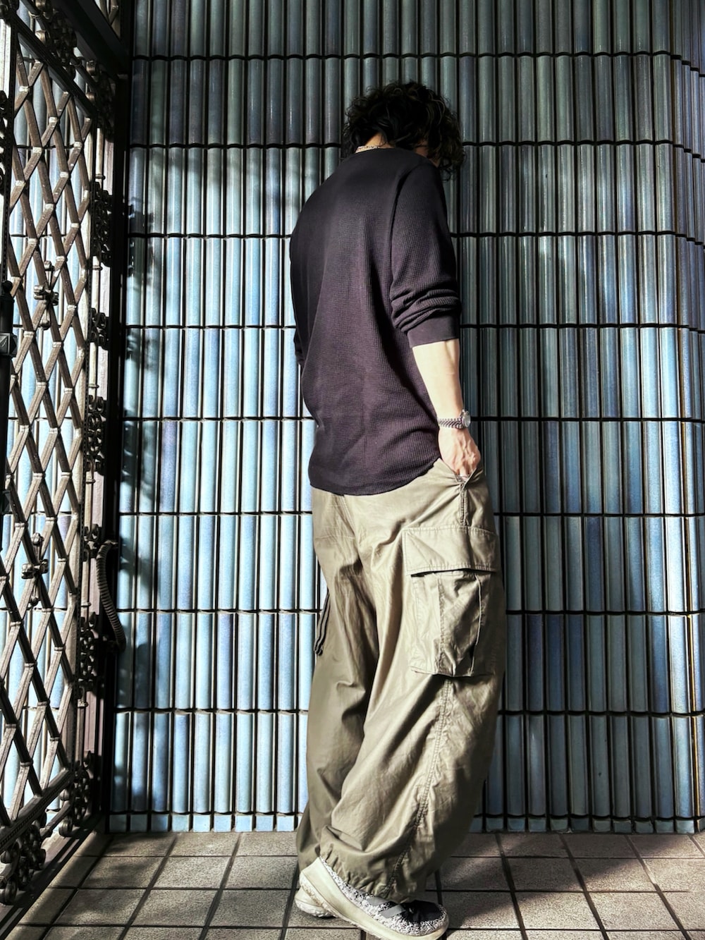 ブラック系のスニーカー、ブラック系のTシャツ/カットソー、グリーン系のカーゴパンツを着用したメンズの秋コーディネートの4枚目の写真