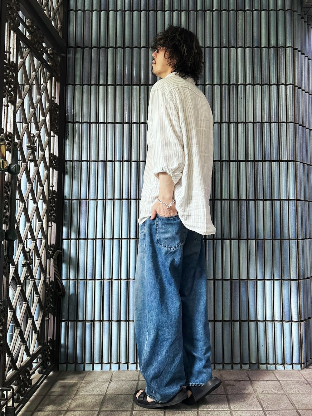 ブラック系のサンダル、ホワイト系のシャツ/ブラウス、ブルー系のデニムパンツを着用したメンズの夏コーディネートの4枚目の写真