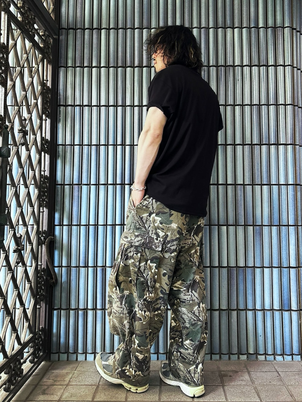 グリーン系のカーゴパンツ、グレー系のスニーカー、ブラック系のTシャツ/カットソーを着用したメンズの春コーディネートの4枚目の写真