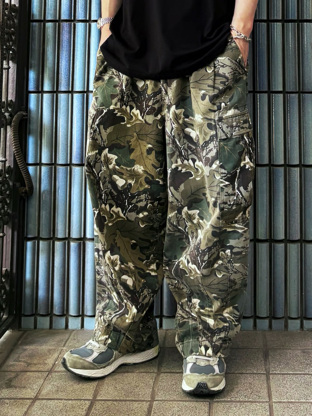 グリーン系のカーゴパンツ、グレー系のスニーカー、ブラック系のTシャツ/カットソーを着用したメンズの春コーディネートの3枚目の写真