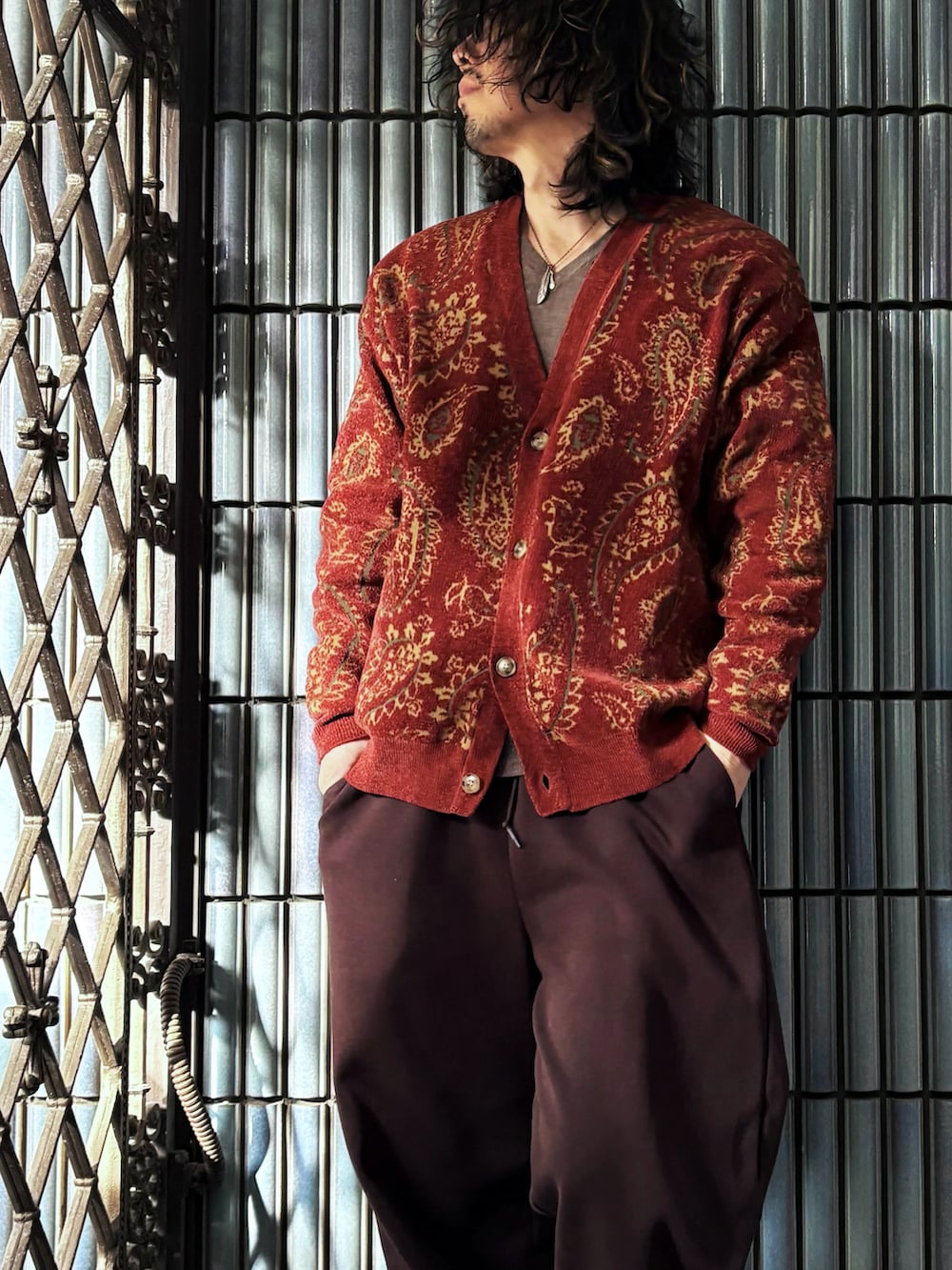 レッド系のカーディガン/ボレロ、ブラウン系のニット/セーター、ブラウン系のスウェットパンツを着用したメンズの冬コーディネートの2枚目の写真