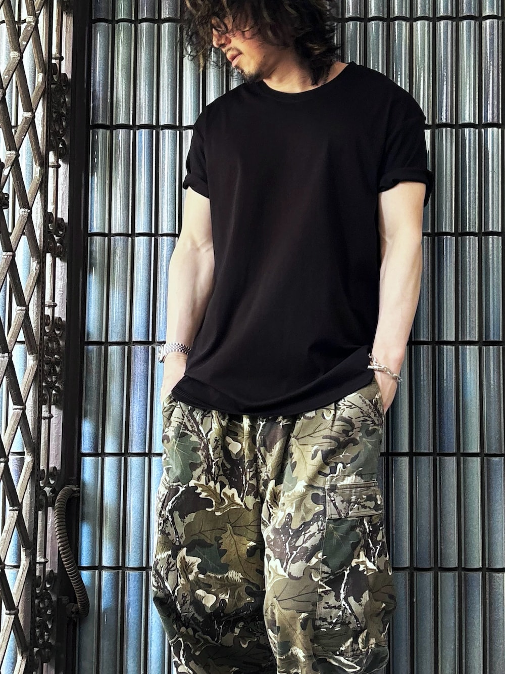 グリーン系のカーゴパンツ、グレー系のスニーカー、ブラック系のTシャツ/カットソーを着用したメンズの春コーディネートの2枚目の写真
