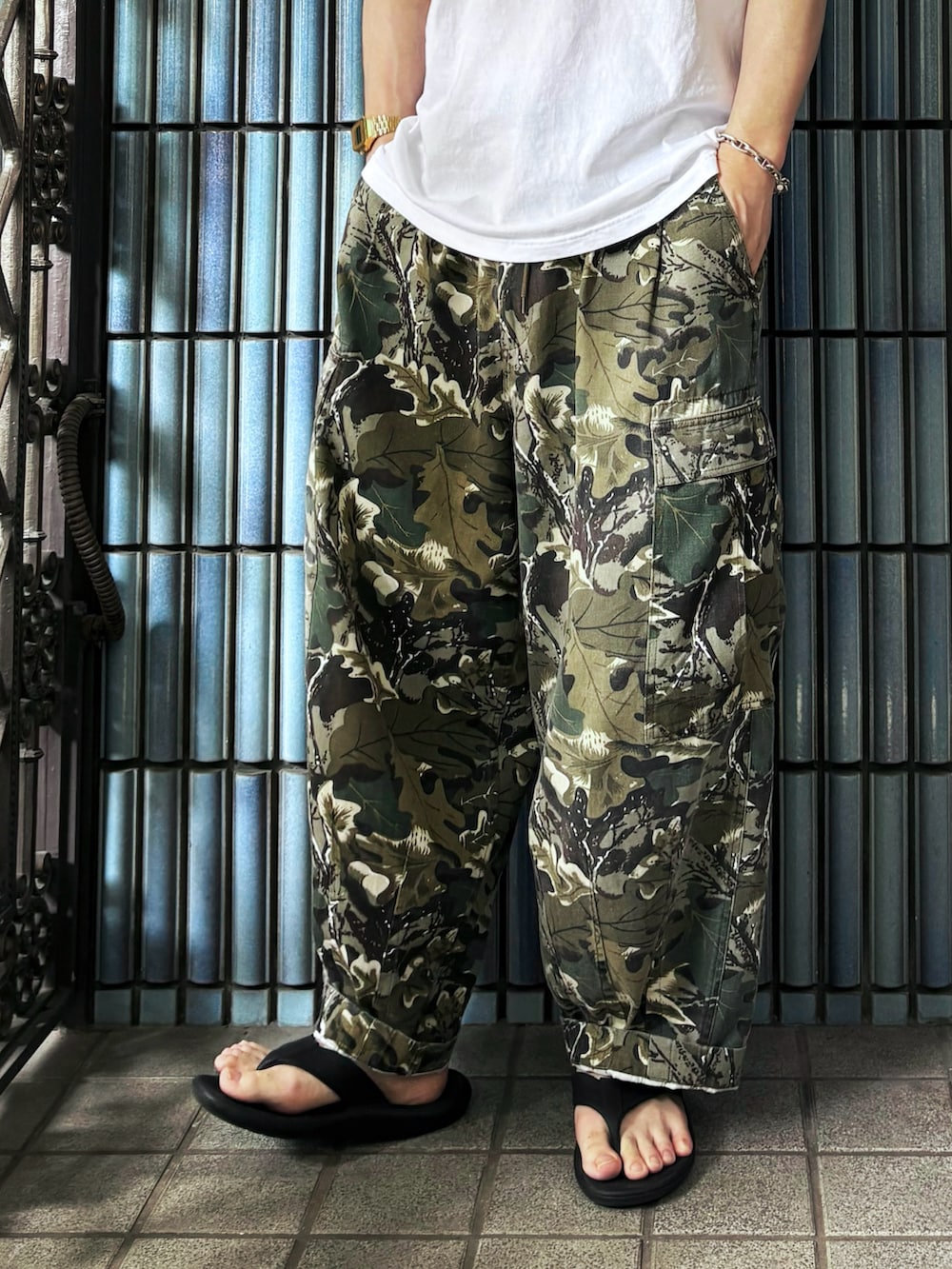 ブラック系のサンダル、グリーン系のカーゴパンツ、ホワイト系のTシャツ/カットソーを着用したメンズの夏コーディネートの3枚目の写真