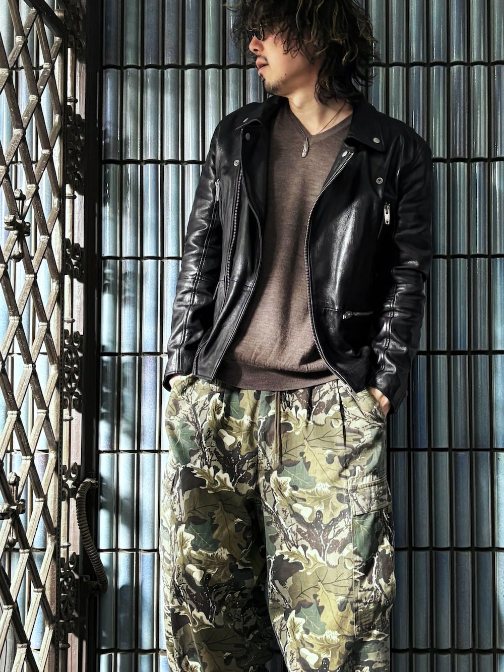 ブラウン系のニット/セーター、グリーン系のカーゴパンツ、ブラック系のスニーカーを着用したメンズの春コーディネートの2枚目の写真