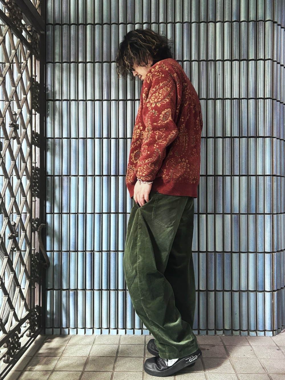 レッド系のカーディガン/ボレロ、ブラウン系のニット/セーター、ブラック系のスニーカーを着用したメンズの春コーディネートの4枚目の写真