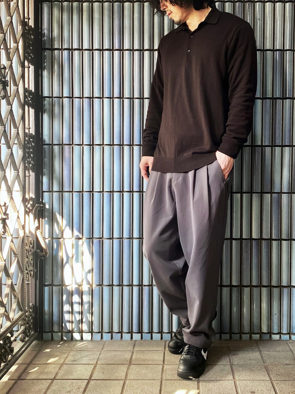 ブラウン系のポロシャツ、グレー系のその他パンツ、ブラック系のスニーカーを着用したメンズの春コーディネートの4枚目の写真