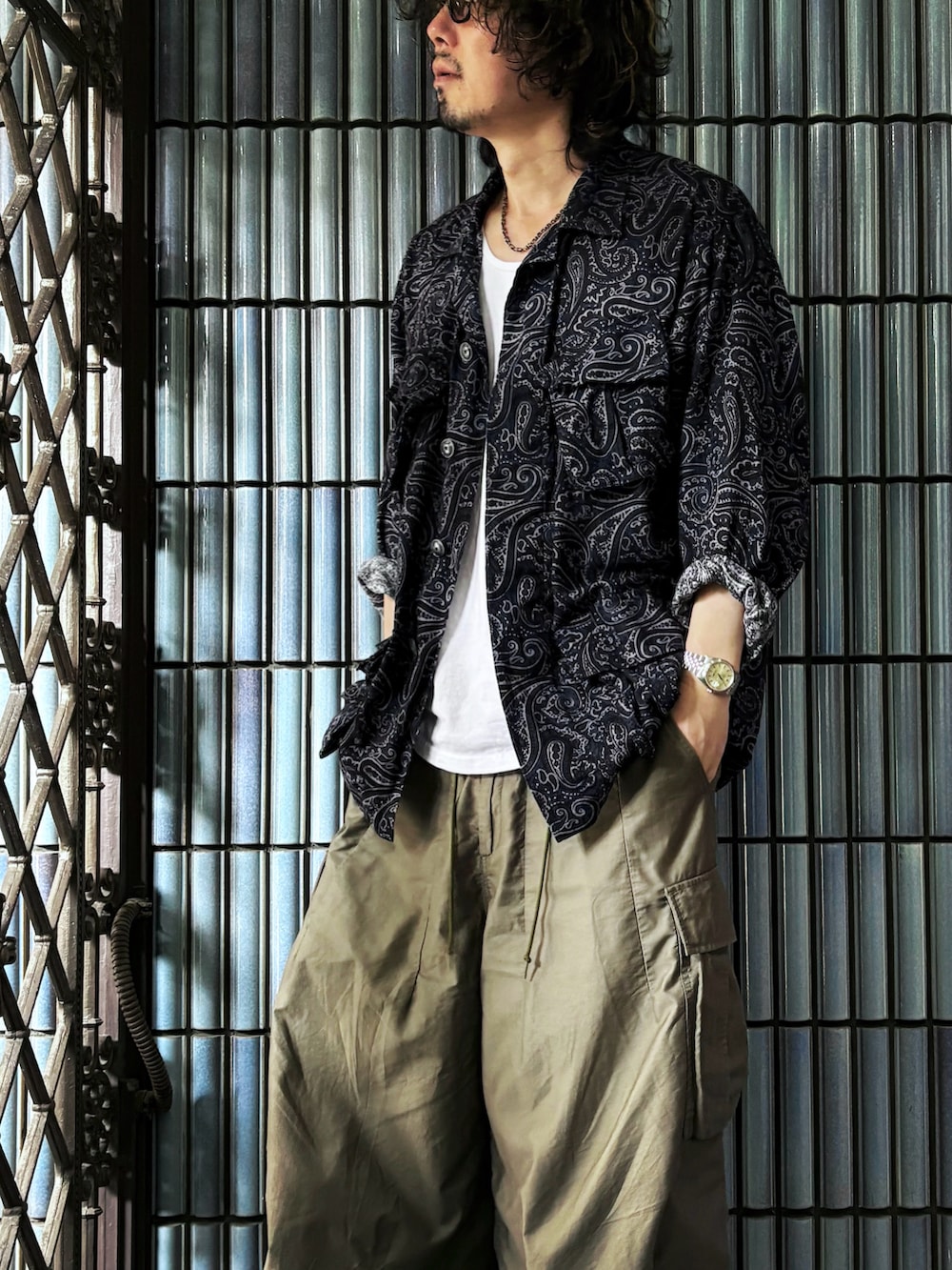 ブルー系のミリタリージャケット、ホワイト系のタンクトップ、グリーン系のカーゴパンツを着用したメンズの秋コーディネートの2枚目の写真