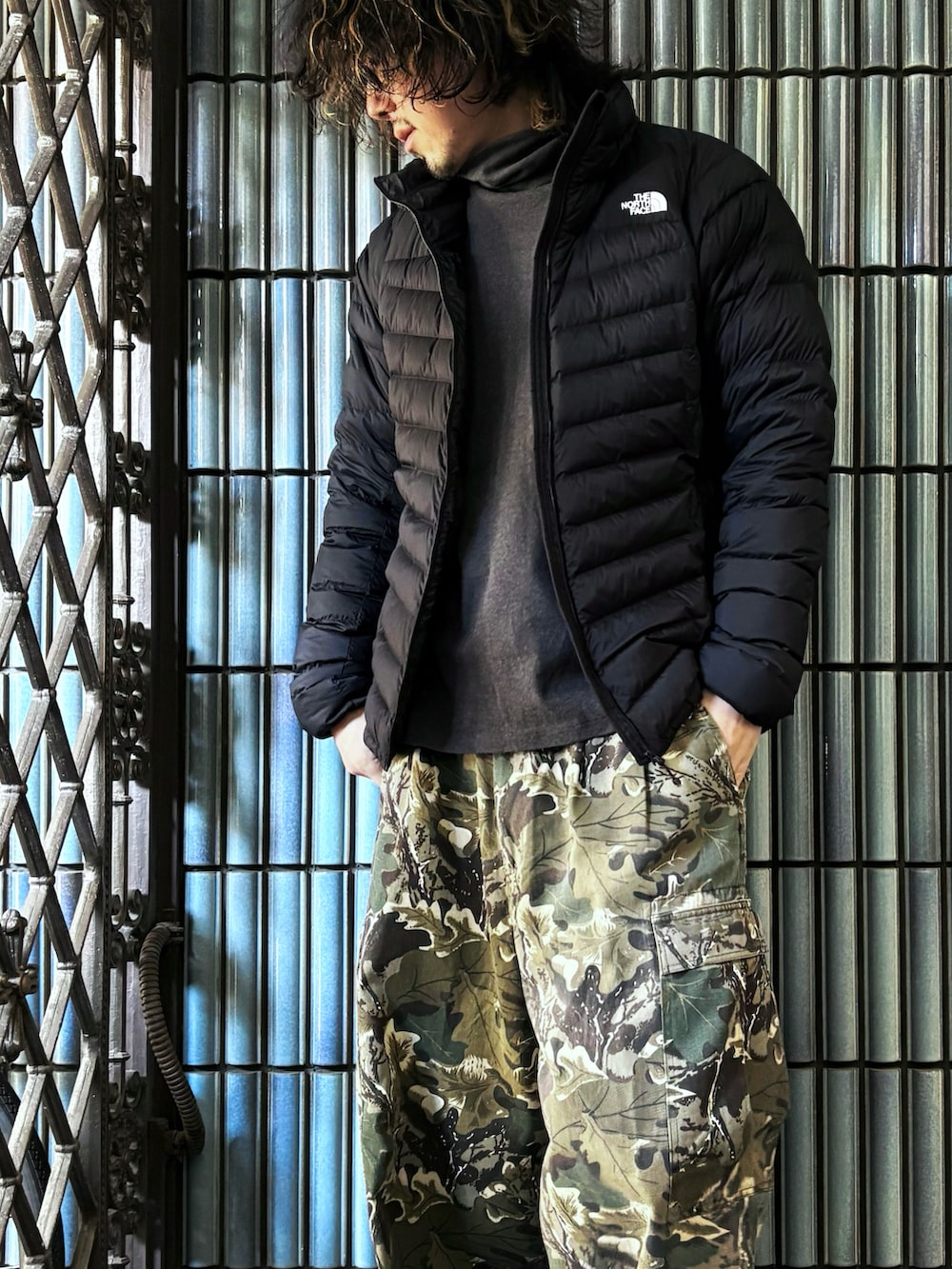 グリーン系のカーゴパンツ、グレー系のスニーカー、グレー系のTシャツ/カットソーを着用したメンズの冬コーディネートの2枚目の写真