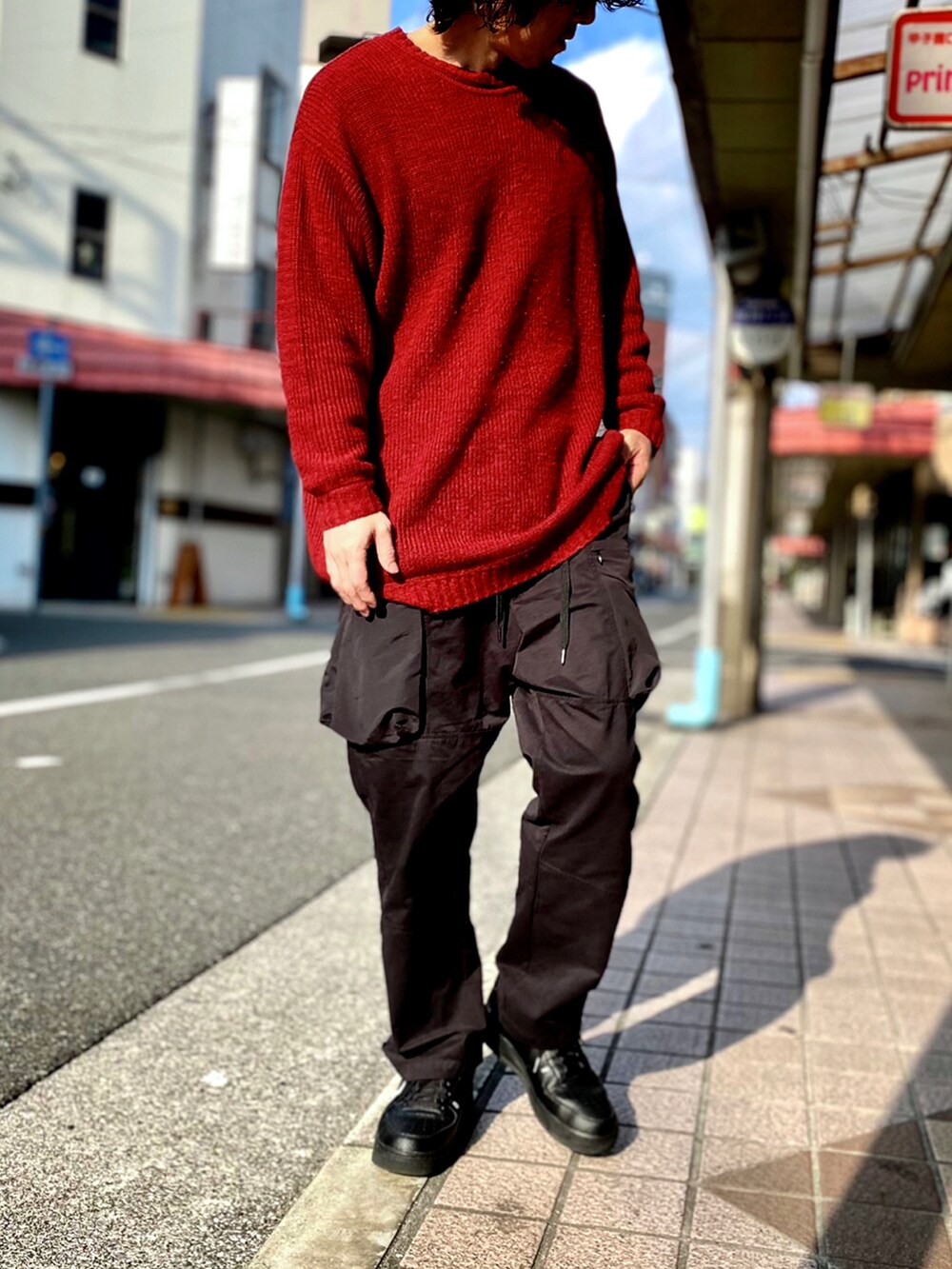 レッド系のニット/セーター、ブラック系のカーゴパンツ、ブラック系のスニーカーを着用したメンズの冬コーディネートの3枚目の写真