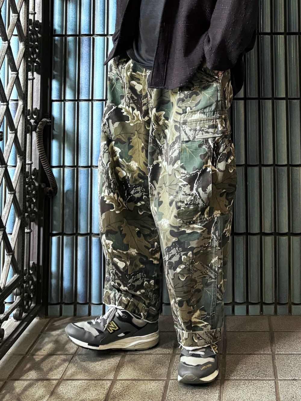 グリーン系のカーゴパンツ、グレー系のスニーカー、ブラック系のシャツ/ブラウスを着用したメンズの秋コーディネートの3枚目の写真