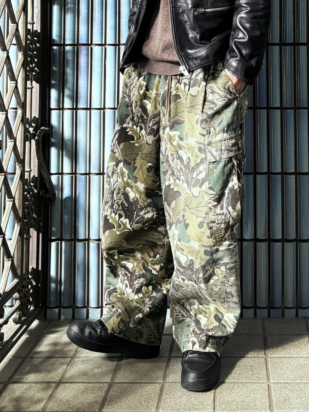 ブラウン系のニット/セーター、グリーン系のカーゴパンツ、ブラック系のスニーカーを着用したメンズの春コーディネートの3枚目の写真