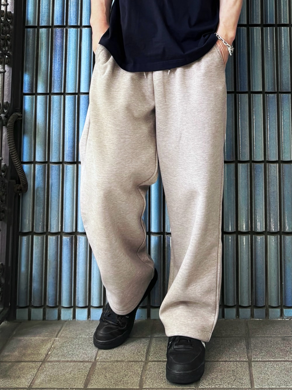 ブラック系のスニーカー、ブルー系のTシャツ/カットソー、ベージュ系のスウェットパンツを着用したメンズの春コーディネートの3枚目の写真