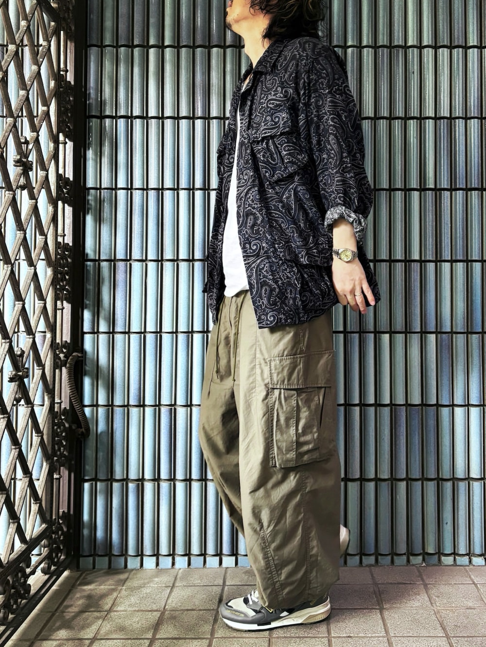 ブルー系のミリタリージャケット、ホワイト系のタンクトップ、グリーン系のカーゴパンツを着用したメンズの秋コーディネートの4枚目の写真