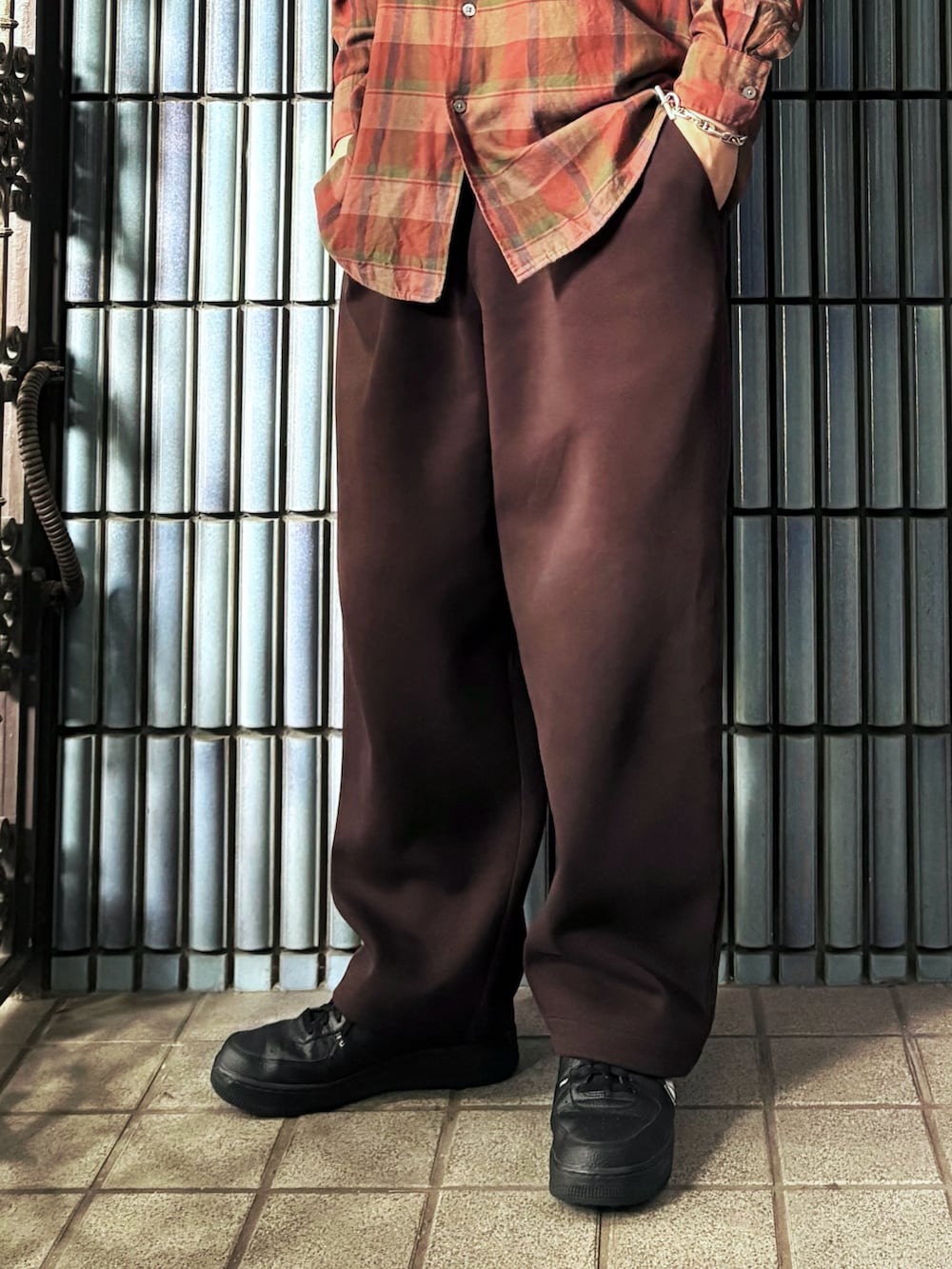 ブラック系のスニーカー、オレンジ系のシャツ/ブラウス、ブラウン系のスウェットパンツを着用したメンズの秋コーディネートの3枚目の写真