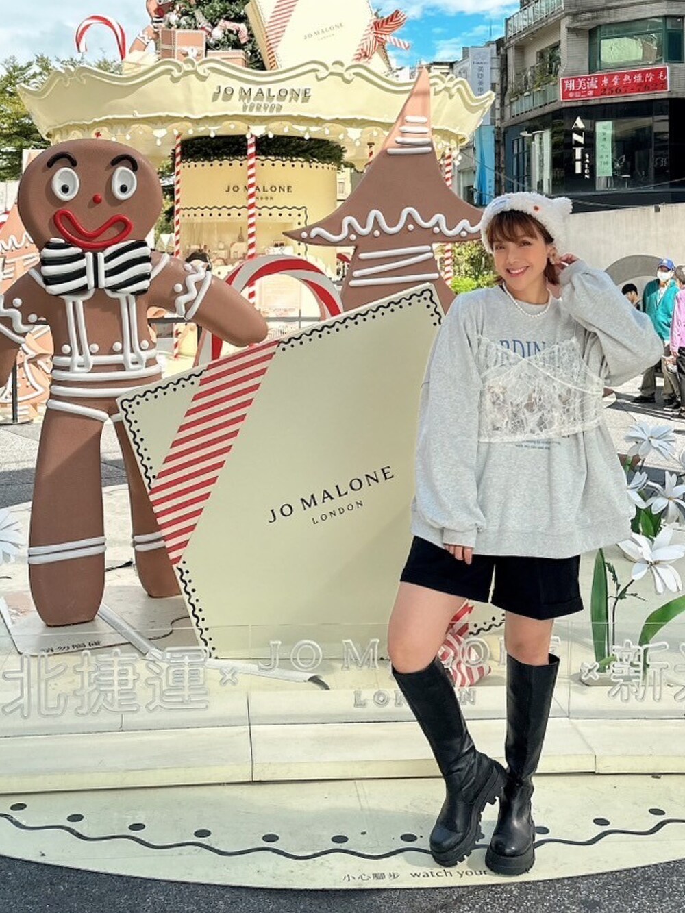 グレー系のスウェット、ブラック系のブーツ、ホワイト系のニットキャップ/ビーニーを着用したレディースの冬コーディネートの2枚目の写真