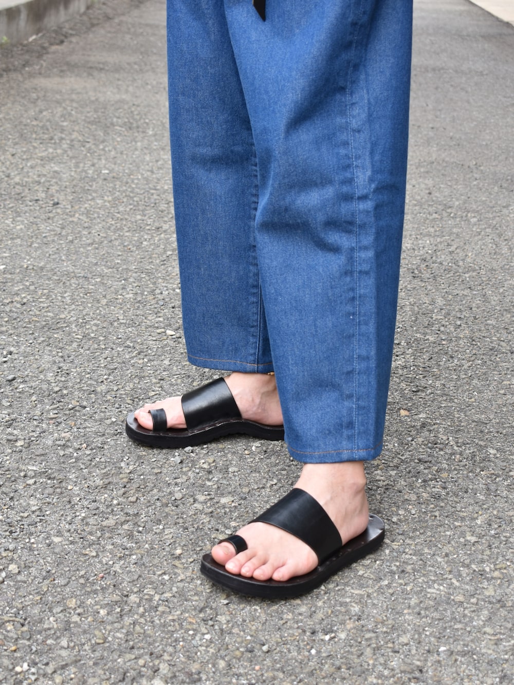 ベージュ系のTシャツ/カットソー、ブルー系のデニムパンツ、ブラック系のサンダルを着用したメンズの夏コーディネートの3枚目の写真