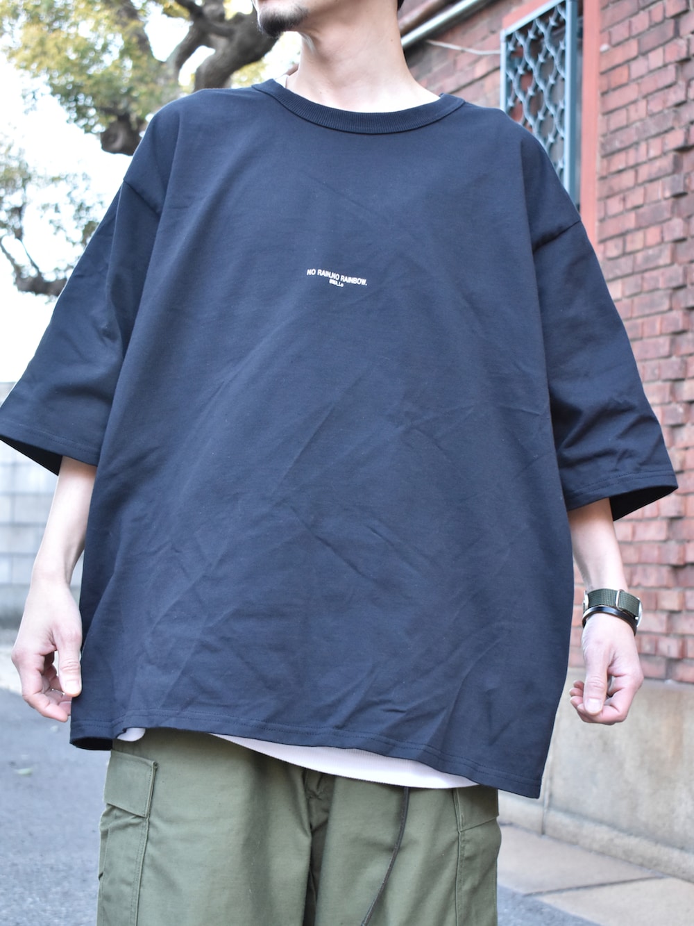 ブラック系のTシャツ/カットソー、グリーン系のカーゴパンツ、ブラック系のスニーカーを着用したメンズの春コーディネートの2枚目の写真