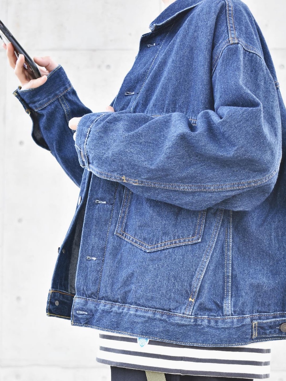 ブルー系のデニムジャケット、ブラック系のTシャツ/カットソー、グレー系のチノパンツを着用したメンズの秋コーディネートの2枚目の写真