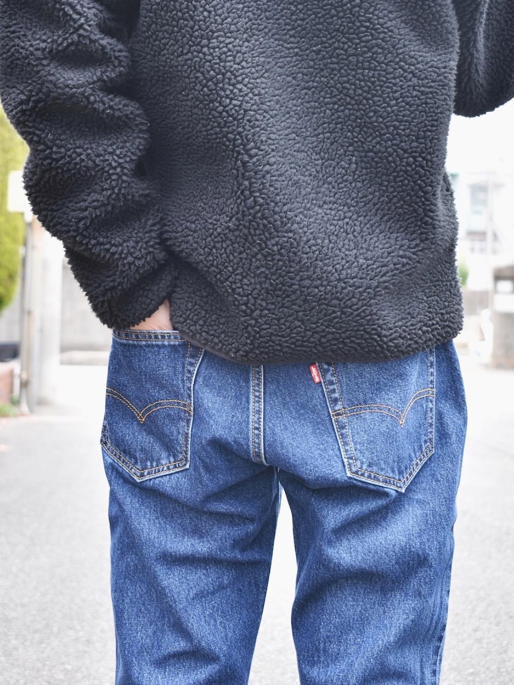 ブラック系のブルゾン、ホワイト系のニット/セーター、ブルー系のデニムパンツを着用したメンズの秋コーディネートの3枚目の写真