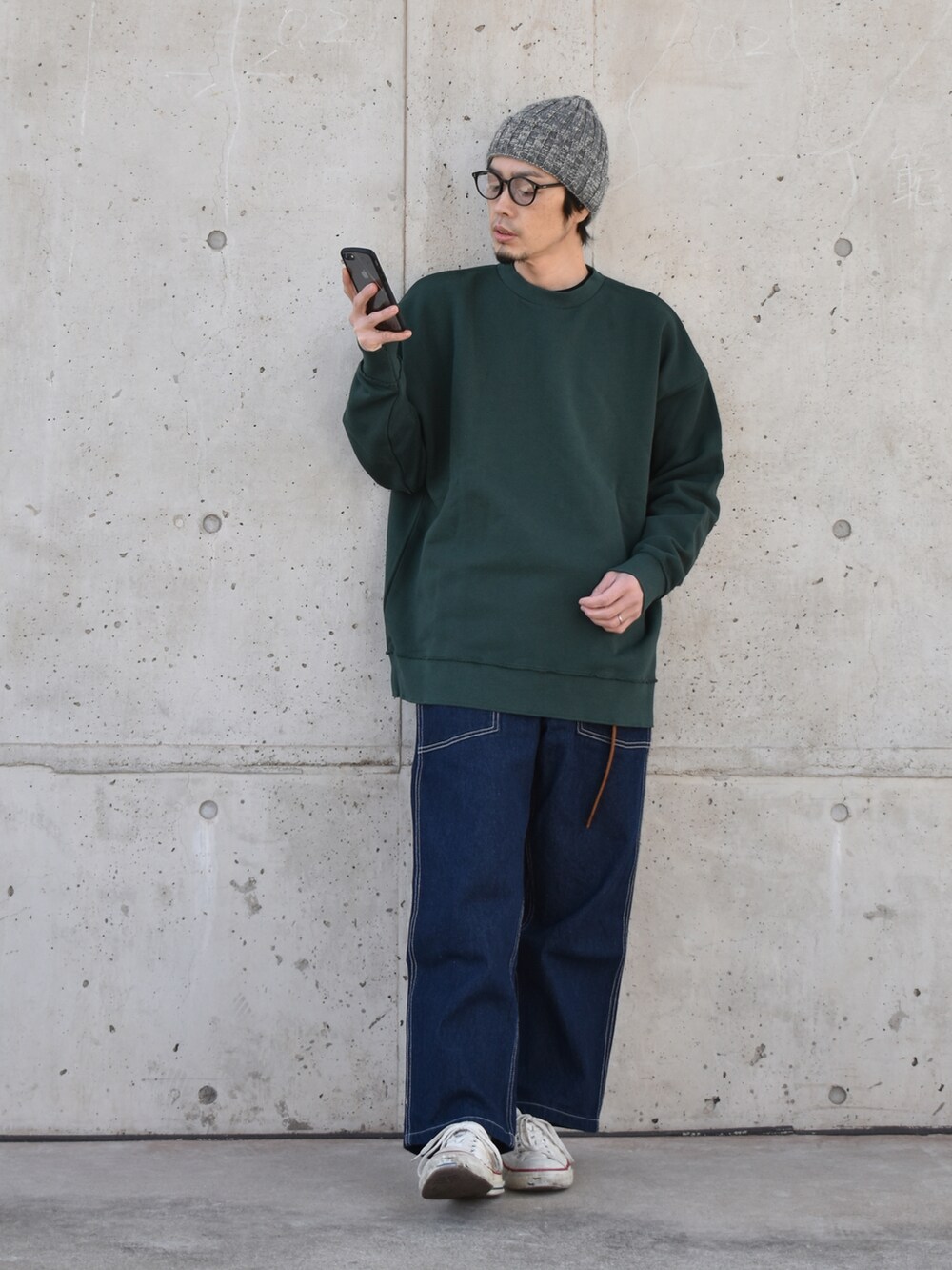 グリーン系のスウェット、ブルー系のデニムパンツ、ホワイト系のスニーカーを着用したメンズの冬コーディネートの2枚目の写真