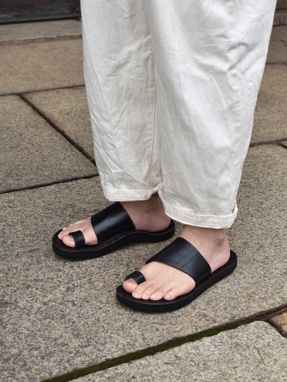 ホワイト系のTシャツ/カットソー、ホワイト系のパンツ、ブラック系のサンダルを着用したメンズの夏コーディネートの3枚目の写真