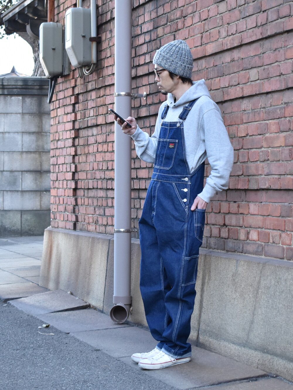 ブルー系のサロペット/オーバーオール、ホワイト系のスニーカー、グレー系のニットキャップ/ビーニーを着用したメンズの冬コーディネートの3枚目の写真