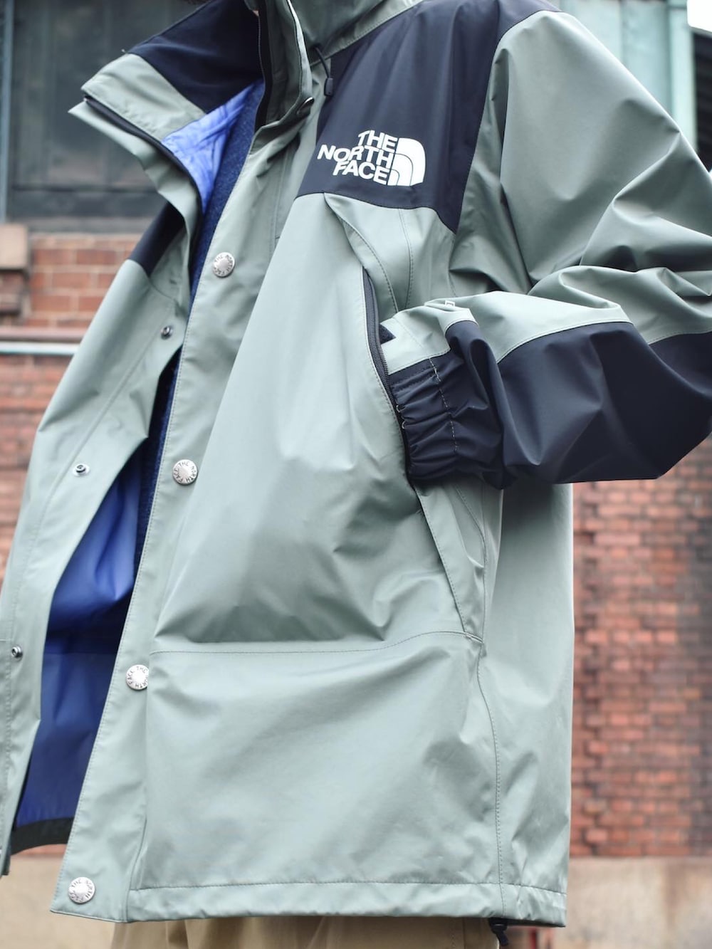 グリーン系のマウンテンパーカー、ベージュ系のその他パンツ、ブラック系のスニーカーを着用したメンズの秋コーディネートの2枚目の写真