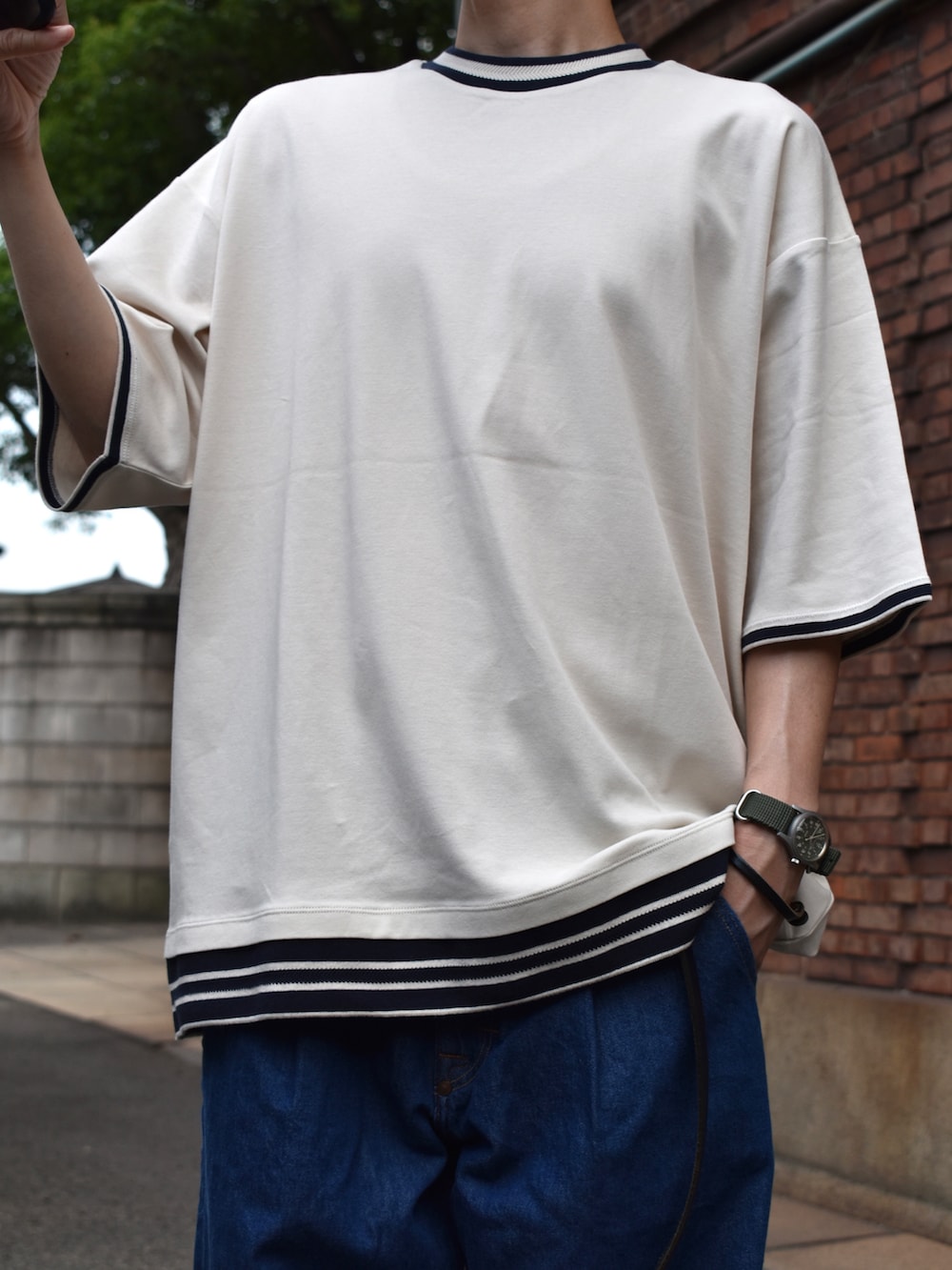 ベージュ系のTシャツ/カットソー、ブルー系のデニムパンツ、ブラック系のサンダルを着用したメンズの夏コーディネートの2枚目の写真