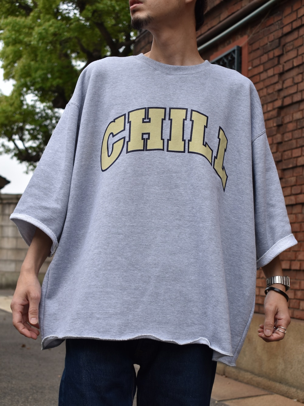 グレー系のスウェット、ブルー系のデニムパンツ、ホワイト系のスニーカーを着用したメンズの春コーディネートの2枚目の写真